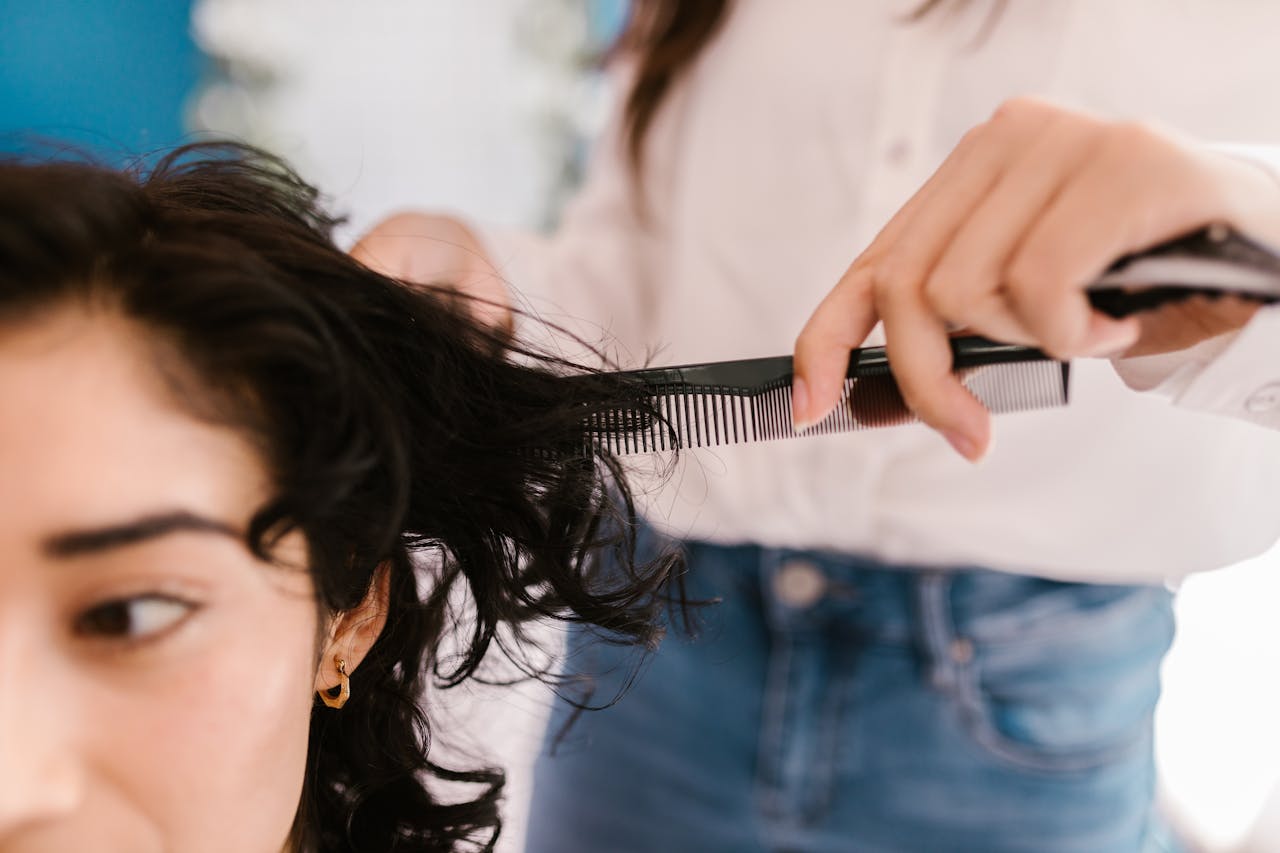 Stylist combing and cutting dark hair