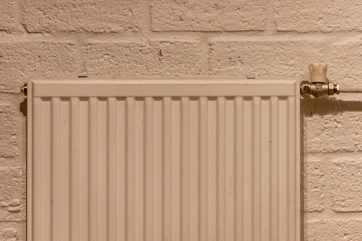Cream panel radiator with brass thermostatic valve.